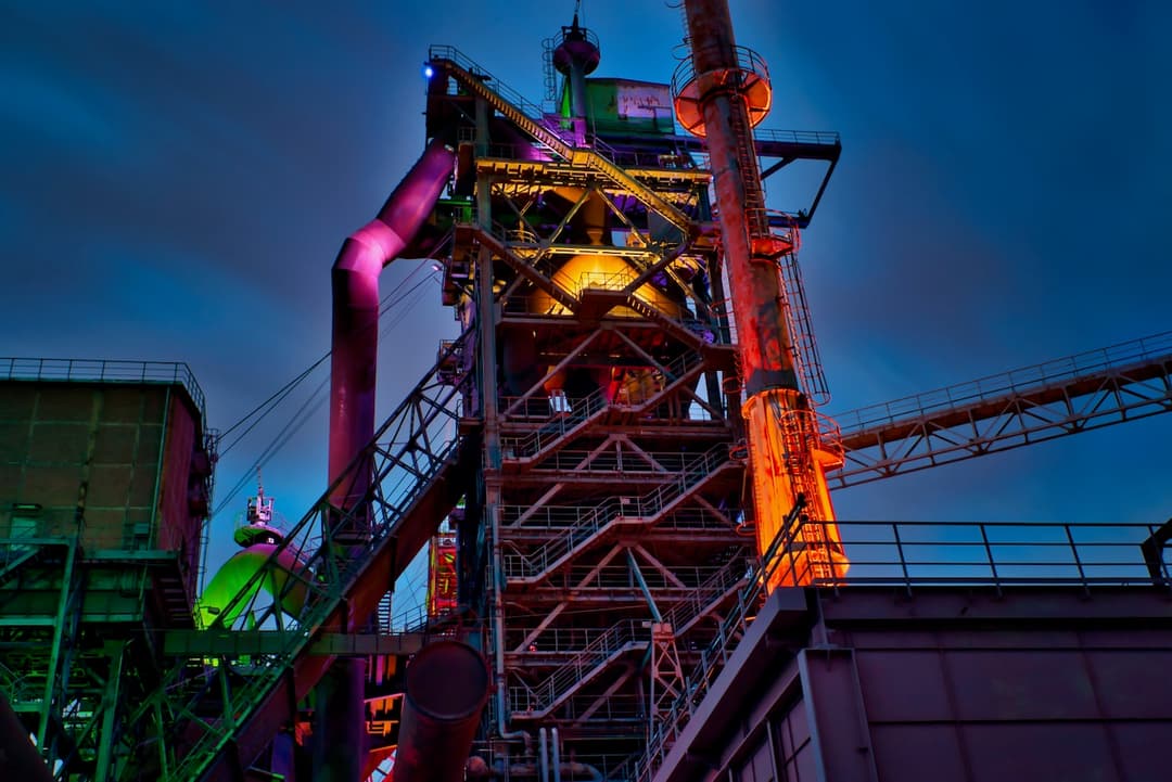 Estructura industrial de gran tamaño iluminada con luces de colores en un entorno nocturno.