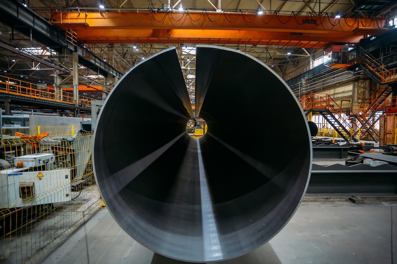 Tubería de acero vista desde el interior, en un entorno industrial con características de manufactura.